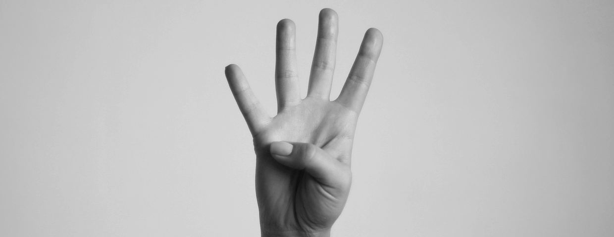 Black and white photo of a hand gesturing number 4 on blank background