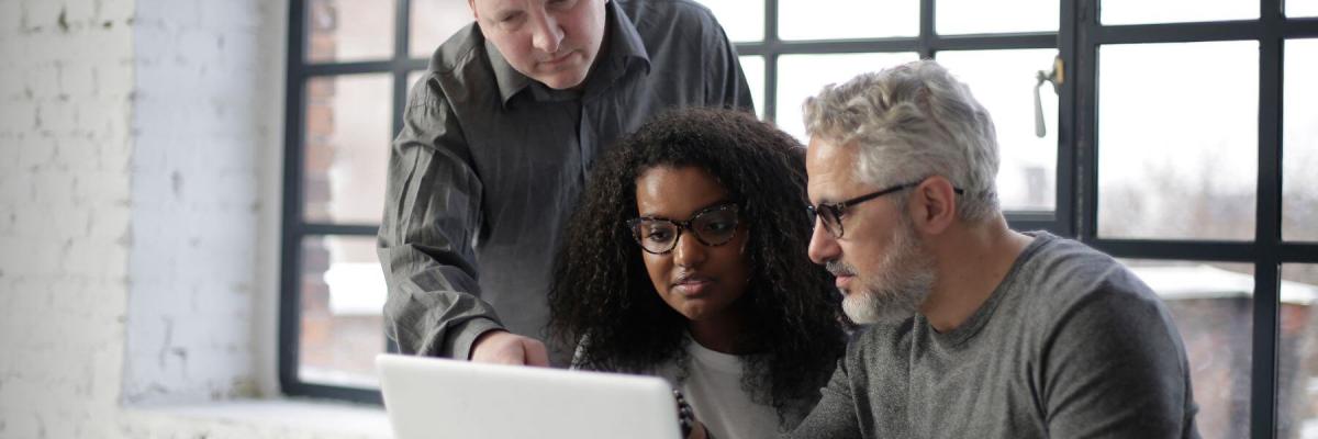 three coworkers reviewing laptop screen