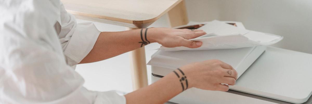 person touching printed documents on top of a printer