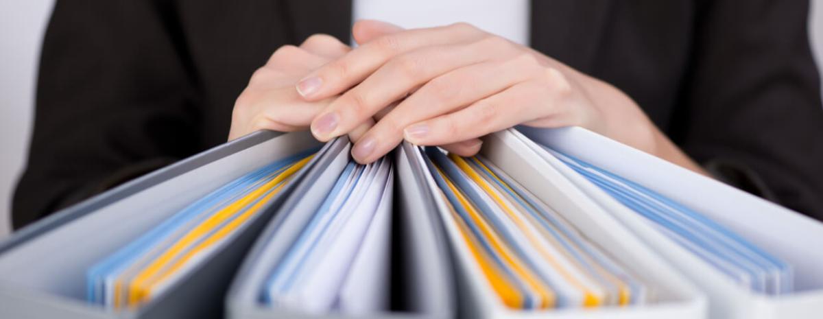 Woman laying both hands on binders full of documents.